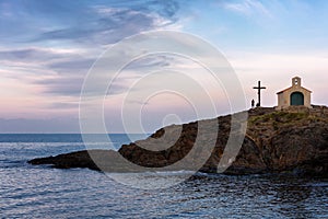Tourists seeing the sunset near a cross of the Saint Vincent Chapel in Collioure on the south of France