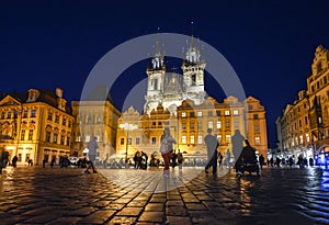 Tourists sightsee late at night in Old Town Square under the lighted towers of Our Lady Before Tyn Church in the Prague Czechia