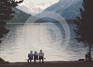 Tourists sit on a bench on the shore of the Alpine lake