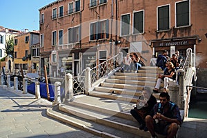 Tourists sitting on a bridge in Venice, Itlay