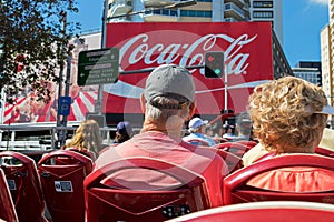 Tourists sitting on the deck of Hop on - Hop off City sightseein