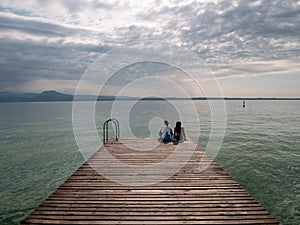 Tourists Sitting on jetty on Lake Garda in Sirmione