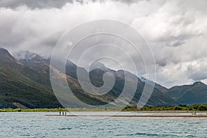 Tourists standing on the shore of Dart River in Glenorchy, New Zealand