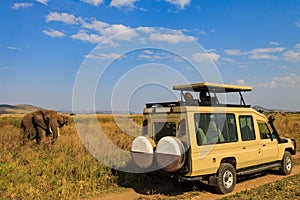 Tourists in SUV car watching and taking photos of african elephants in Serengeti national park, Tanzania