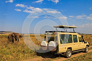 Tourists in SUV car watching and taking photos of african elephants in Serengeti national park, Tanzania