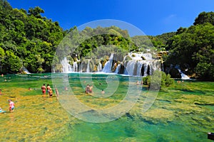 Tourists swim in the lake near picturesque cascade waterfall in the Krka National Park, Croatia in summer. The best big beautiful