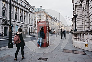 Tourists take photos by red phone booth in Regent Street St. James, London, UK