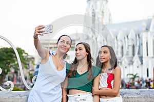 Tourists taking a selfie at the Ortiz Bridge with La Ermita church on background in the city of Cali in Colombia photo