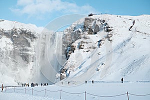 Tourists in to Iceland waterfall Skogafoss in Icelandic nature landscape view in winter season, The Skogafoss is one of the bigges