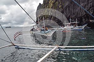 Tourists on traditional philippino fisherman boats crossing the waters of El Nido at Palawan Island the Philippines
