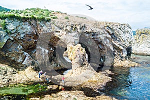 Tourists/trekers evaluating natural arch. Aerial drone photo of cape Ptichiy, Sakhalin island, Russia near by cape Velikan.