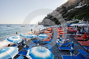 Tourists on Tyrrhenian sea, Amalfi coast, sunbed with umbrellas in beach Positano, Italy