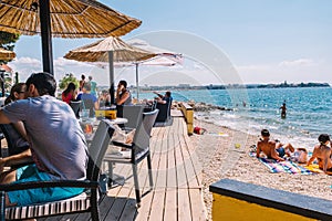 Tourists and various guests sitting at the bar by the sea and enjoy the sun in Zadar