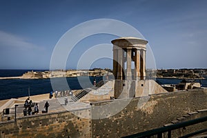 Tourists visiting a Siege Bell War Memorial on the sea coast, Valletta, Malta.