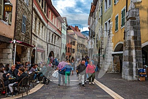 Tourists and visitors walking in the beautiful streets of Annecy town against a cloudy sky. Annecy, Haute Savoie, France