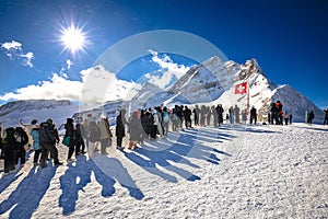 Tourists waiting in line to take a photo in front of Swiss flag on Jungfraujoch peak