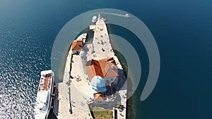 Tourists walk around the church on the island of Gospa od Skrpjela. Drone