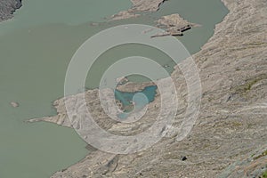 Tourists walk on melt Pasterze glacier by Grossglockner from kaiser-franz-josefs-hoehe in Austria