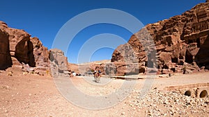 Tourists walking along Facades Street in the plains of the city of Petra.