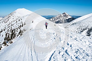 Tourists walking along the ridge of snowy mountains