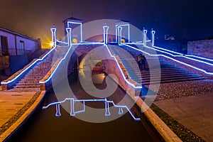 Tourists walking on the bridge Trepponti, Comacchio, Italy by night. photo