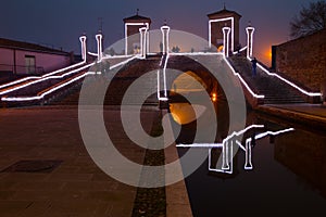 Tourists walking on the bridge Trepponti, Comacchio, Italy by night. photo