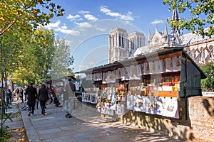 Tourists walking by the famous bookseller's boxes (bouquinistes) along the Seine River near Notre Dame in Paris