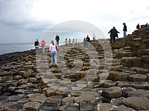 Tourists walking on Giant's Causeway's basalt columns