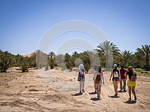 Tourists walking in the Oasis of Merzouga village in Sahara desert, Morocco