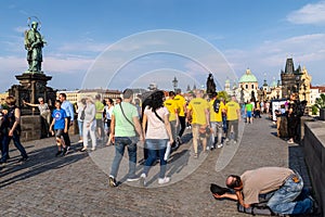 Tourists walking & posing for pictures while ignoring a begger in Charges Bridge, Prague