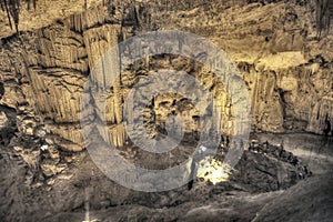 Tourists walking on stalactites cave looking infernal