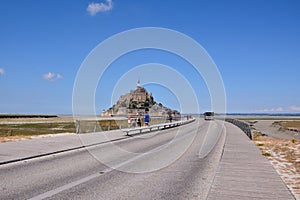 Tourists walking to the famous historic Le Mont Saint-Michel tidal island in France photo