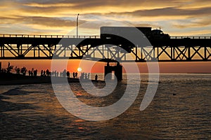 Tourists watching sunset by Lake Michigan under Mackinac Bridge, Mackinaw City, Michigan, USA