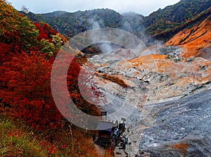 Tourists on a wooden terrace admire the awesome barren terrain with volcanic activities hot steam vents, sulfurous streams photo