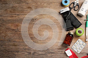 Tourniquet, elastic bandage, scissors and pills on wooden table, flat lay. Space for text