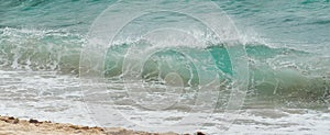 Tourqoise waves breaking on a beach. Summer image is banner shaped.