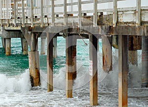 Tourquoise waves breaking on a beach next to a pier. photo