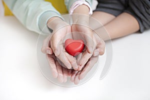 Tow child holding red heart, closeup. Adoption concept