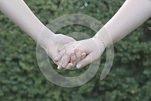 Tow girls holdings hands on a green background