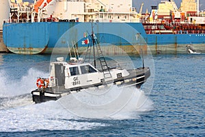 Tow pilot transits in the calm channel of the port of Genoa