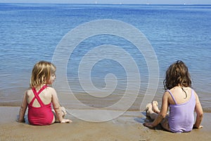 Tow sisters sit on beach bathing suit swimsuit