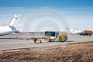 Tow tractor with towbar and tank truck aircraft refuelers moves at the airport apron