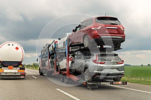 Tow truck car carrier semi trailer on highway carrying batch of damaged cars sold on insurance car auctions for repair and