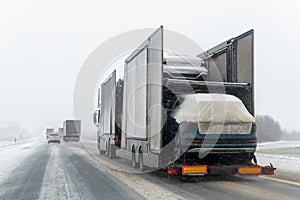 Tow truck car carrier semi trailer on highway carrying batch of new wrapped electric SUVs on motorway road at heavy