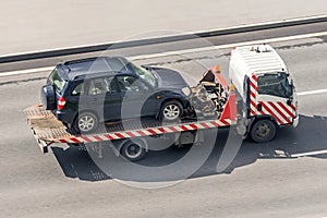 Tow truck carries an evacuated car on a highway, aerial view