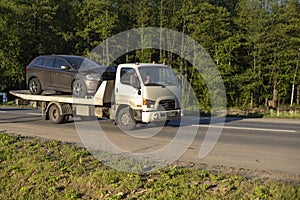 A tow truck is driving a car after an accident. Car transportation on a cargo platform