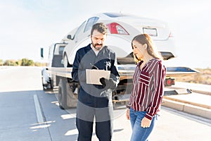 Tow truck operator and female driver checking the invoice