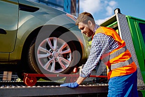 Tow truck operator fixing the car on platform