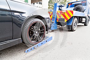 Tow truck towing a broken down car on the street