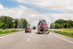 Tow truck trailer on highway carrying three damaged cars sold on insurance car auctions for repair and recovery.  Vehicles